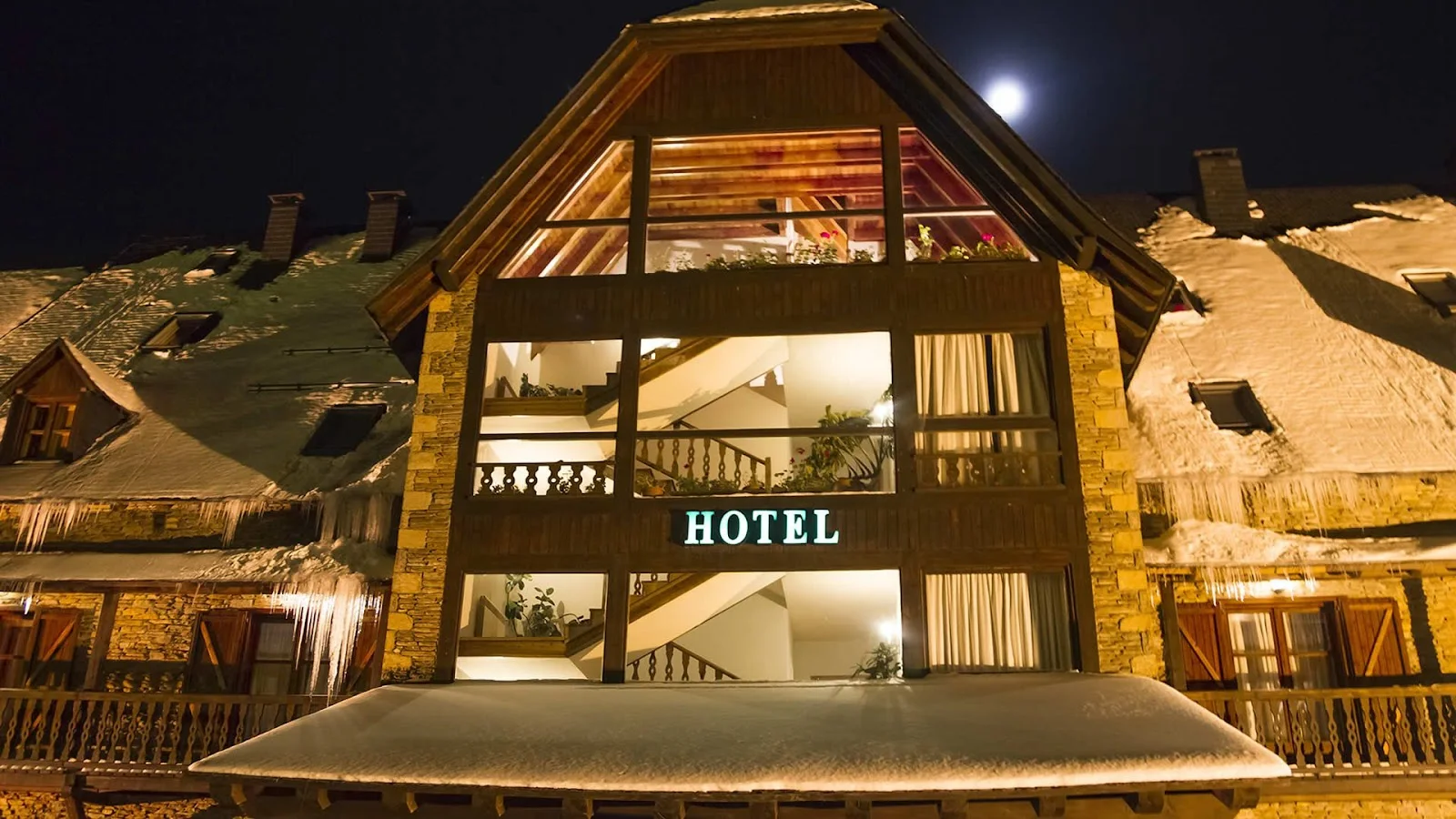 The lit glass-gabled facade of Hotel Chalet Bassibé at Baqueira on a snowy night