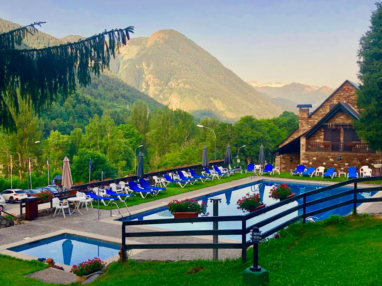 The outdoor pool and stone chalet of Hotel Lacreu in Salardú, with the Aran valley mountains behind