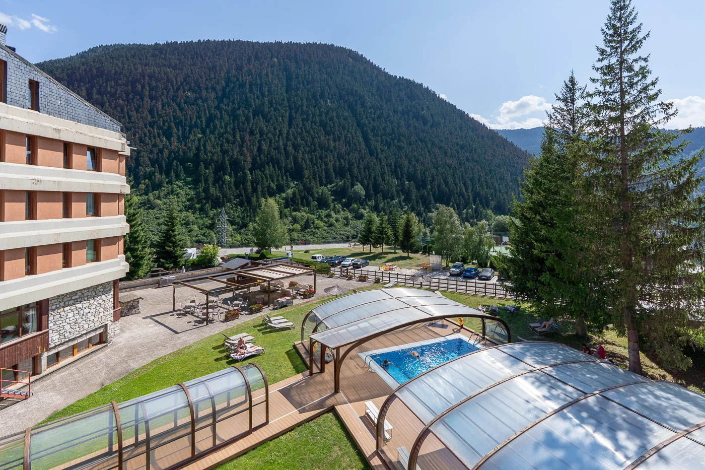 The Hotel Montarto with its covered outdoor pool and terrace, set against a forested Aran mountainside