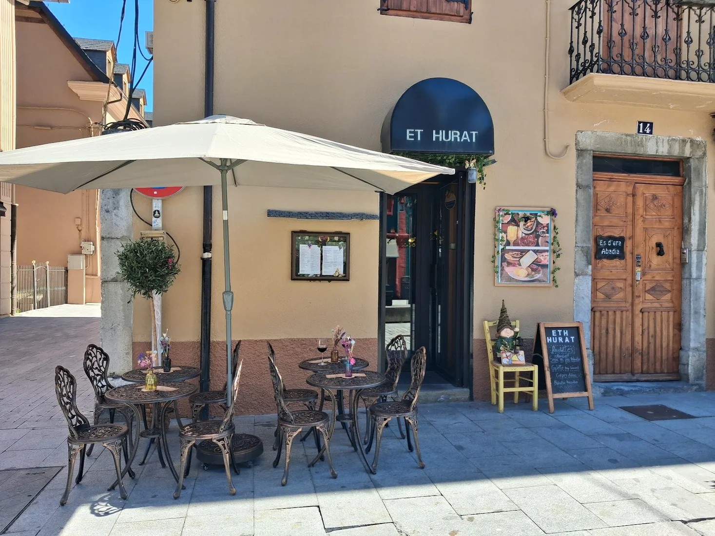 The pavement terrace of Eth Hurat under its awning on a sunny street in old Vielha