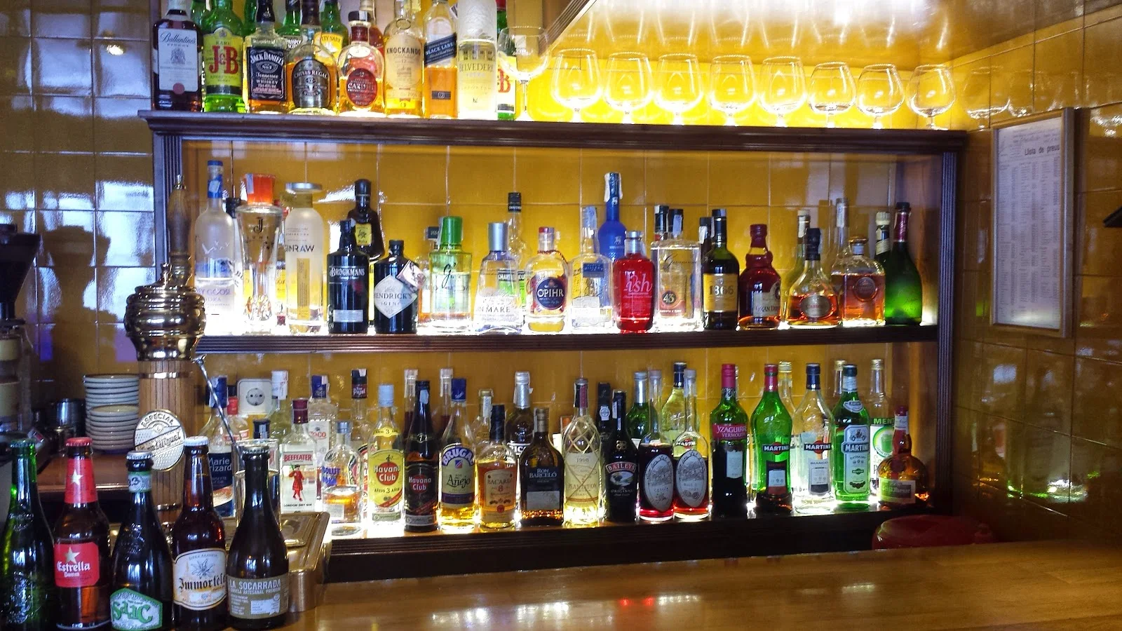 The back bar at La Granja, its shelves lined with spirits and stemware against warm amber tiling