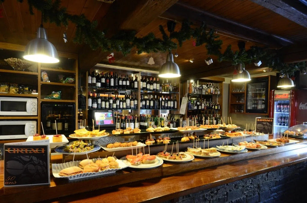 The pintxos counter at Tauèrna Urtau in Arties, piled with pinchos under warm lights