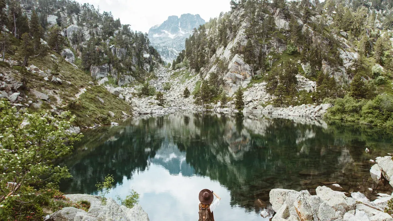 A hiker at a glacial lake in the Aigüestortes national park, near the Val d'Aran in summer