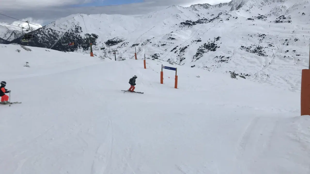 Skiers on a piste at Baqueira Beret beneath the Pyrenees peaks
