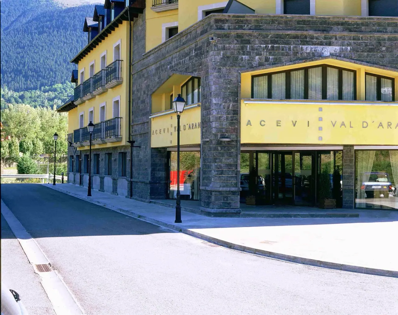 The yellow stone-clad facade and entrance of the Hotel Spa Acevi Val d'Aran in Vielha