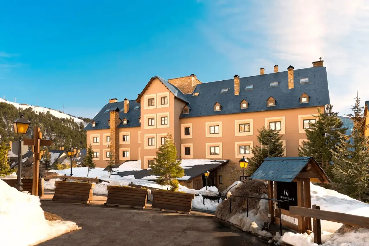 The tan facade and blue-slate roof of the Eurostars Royal Tanau in the snow, with a Eurostars sign at the entrance drive