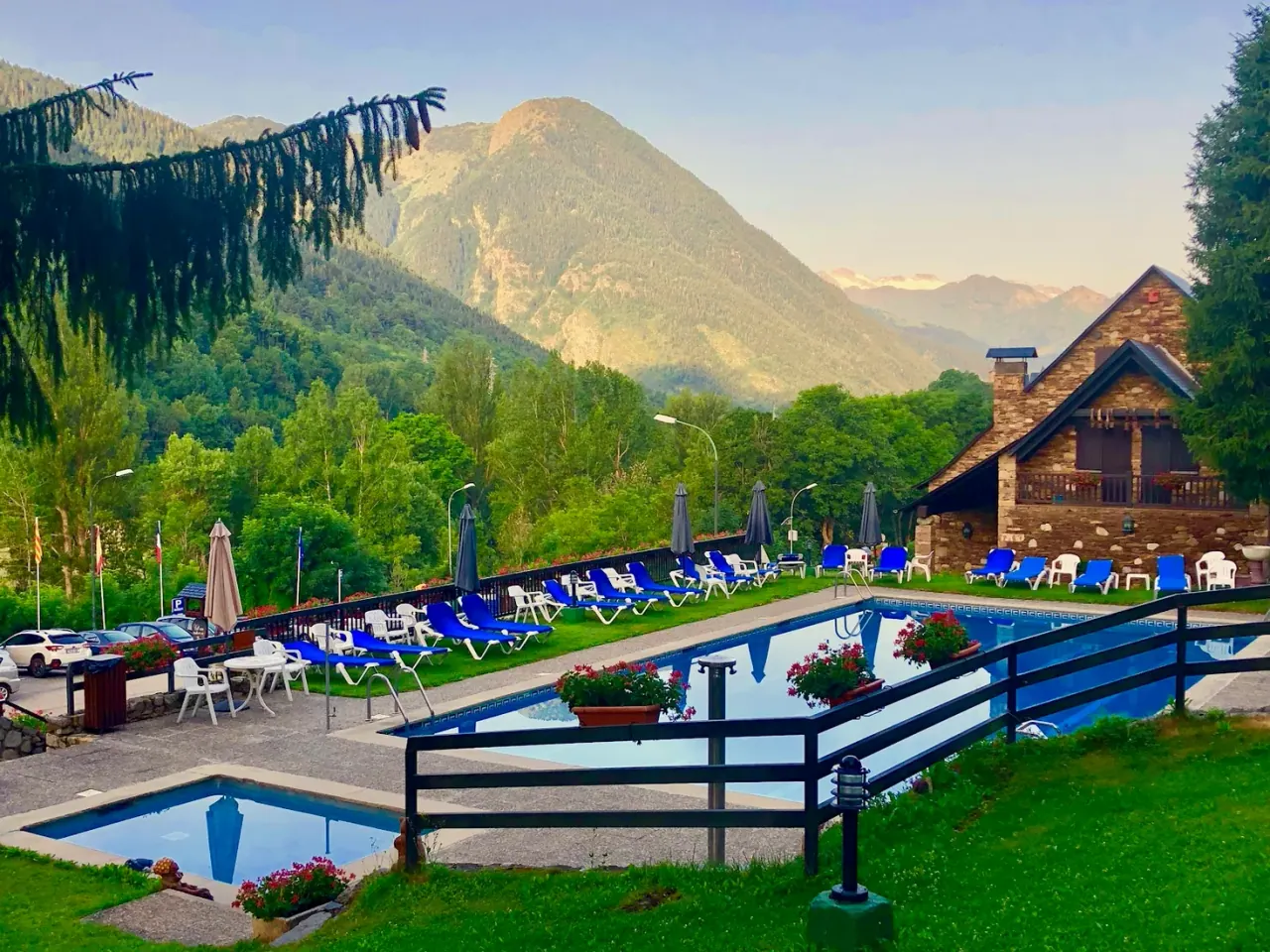 The outdoor pool and stone chalet of Hotel Lacreu in Salardú, with the Aran valley mountains behind
