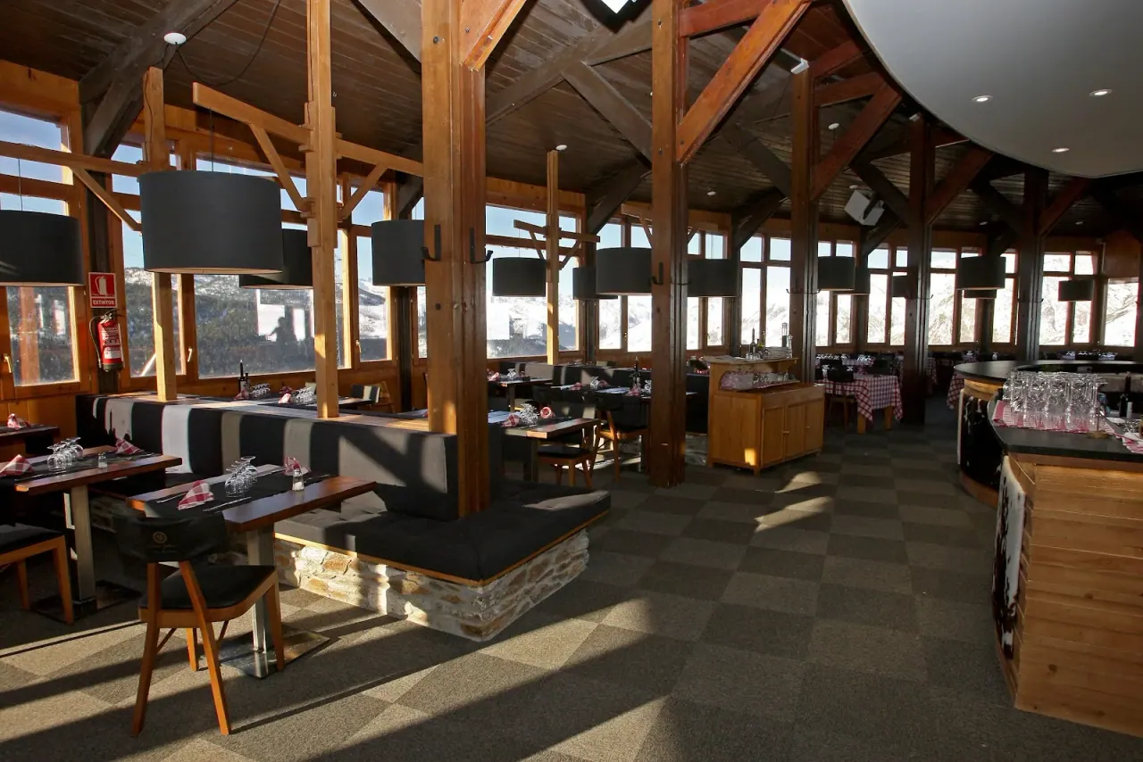 The warm wood-beamed dining room of Cinco Jotas Grill on the Baqueira slopes, with big windows onto the snow